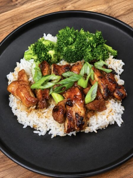 Hot honey chicken thighs coated in sweet and spicy sriracha glaze, served with rice and broccoli. Copy alt text