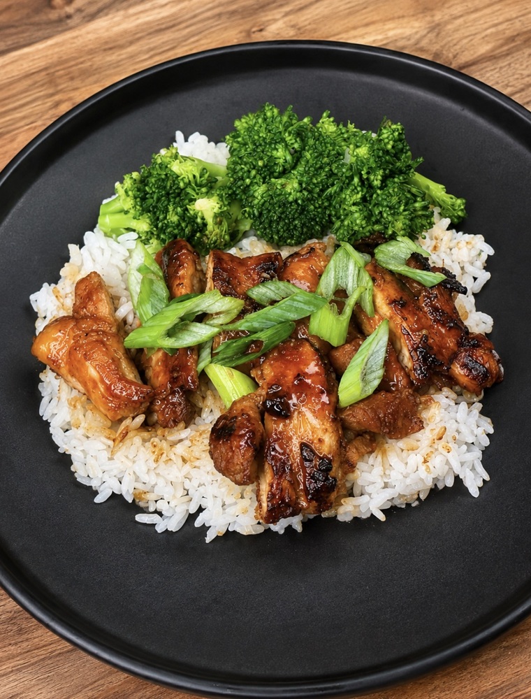 Hot honey chicken thighs coated in sweet and spicy sriracha glaze, served with rice and broccoli. Copy alt text